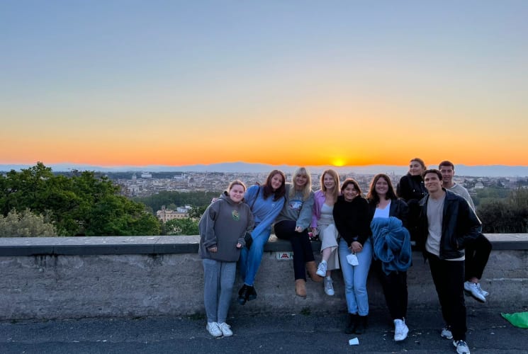 A group of students in front of a view of a sunset.